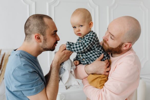 due uomini in atteggiamento affettuoso con un bambino di pochi mesi
